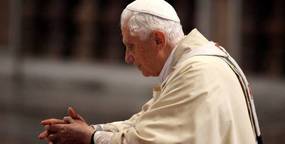 Benedict Prays at John Paul II Coffin.jpg